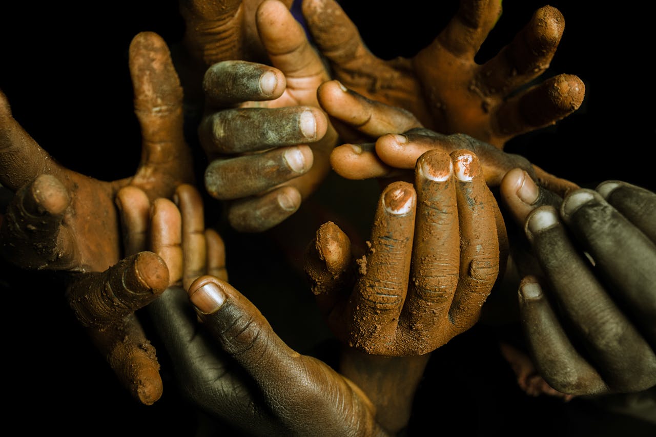 A creative close-up of muddy hands, depicting unity and diversity in an artistic arrangement.