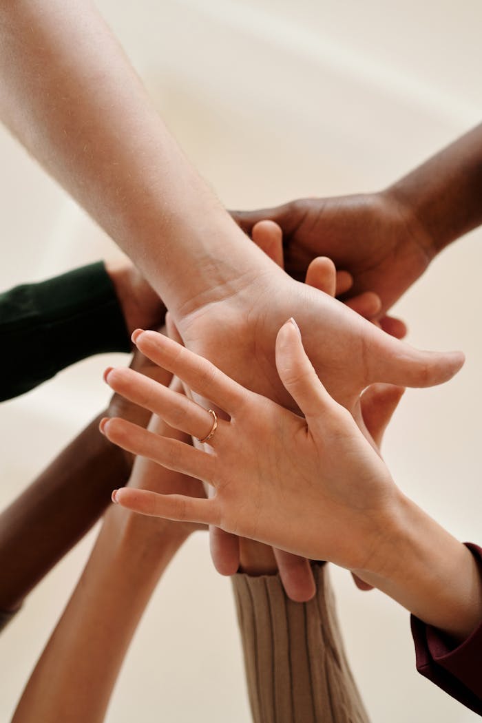 A close-up of diverse hands joined together symbolizing teamwork, cooperation, and unity indoors.